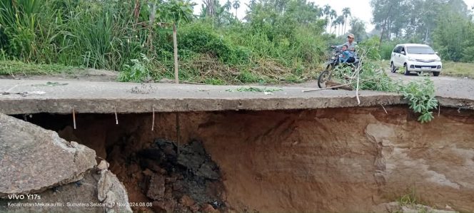 
					Hujan deras menggerus jalan utama di Desa Sinar Marga, Kecamatan Mekakau Ilir, OKU Selatan, hingga nyaris putus total. 